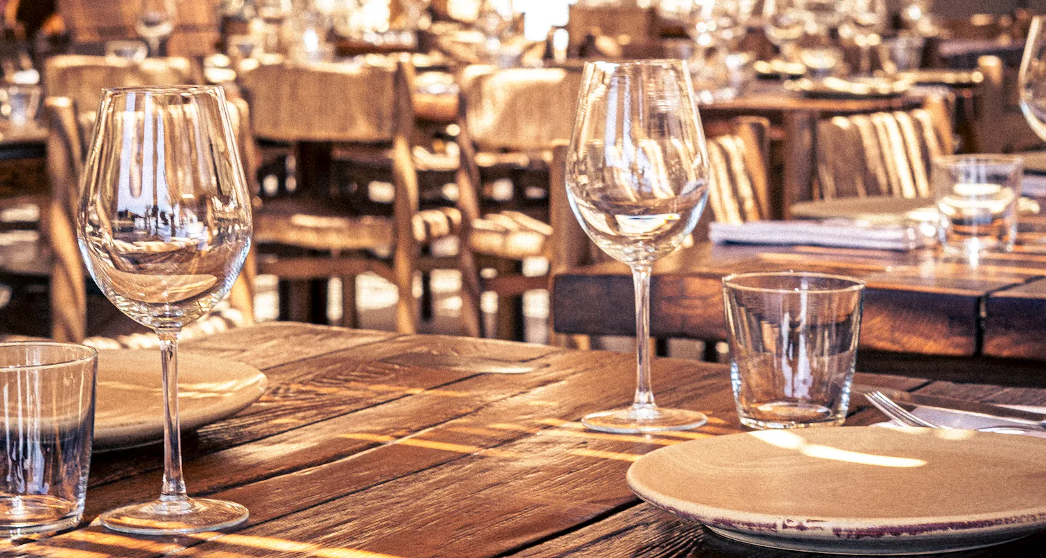 Mesa de madera con copas y platos (foto ilustrativa)